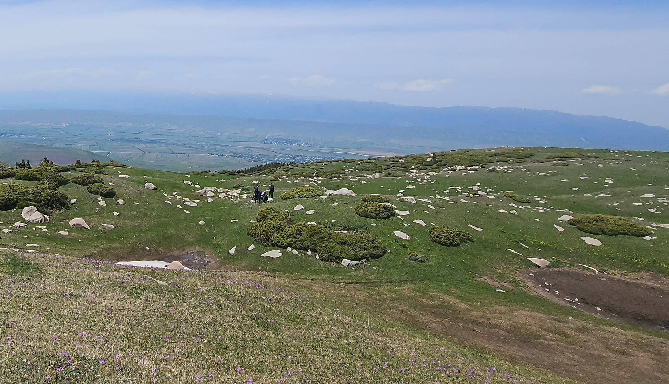 Weites Hochplateau von Ak-Bulak mit Blick in die Talebene, im Gelände ein kleines Begehungsteam