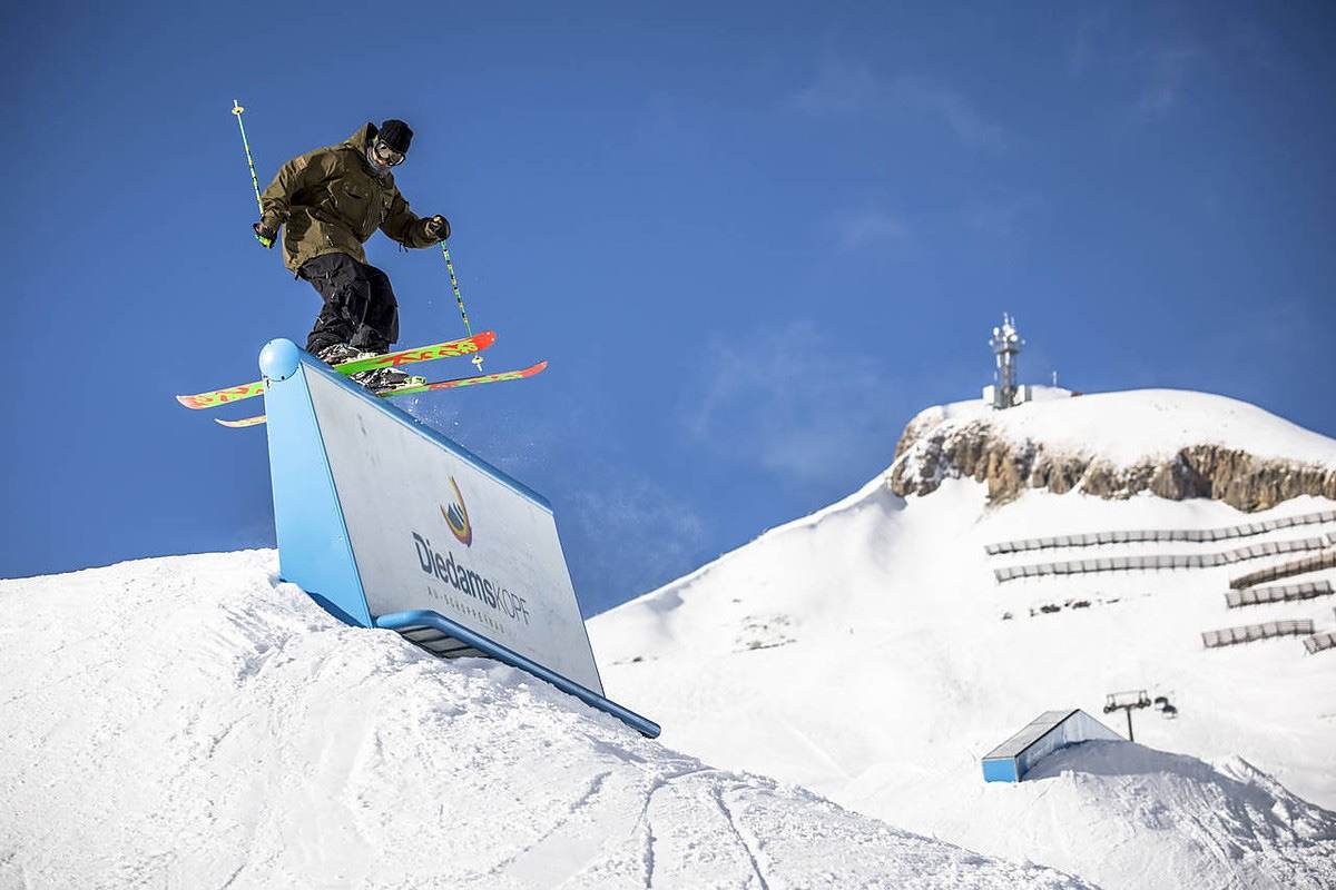 Freeskier auf einer Box im Diedamspark, dahinter der Gipfel des Diedamskopfs