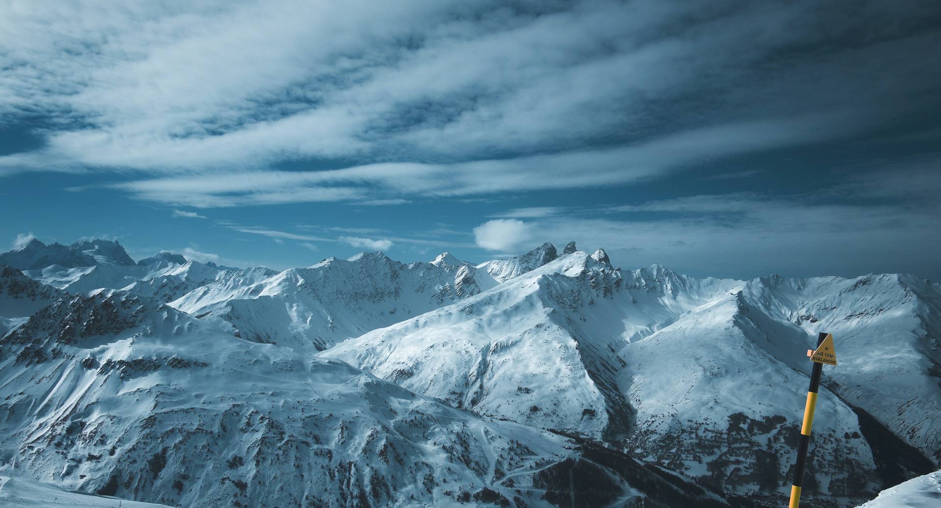 Verschneite Gipfelkette der Alpen unter bewegtem Himmel