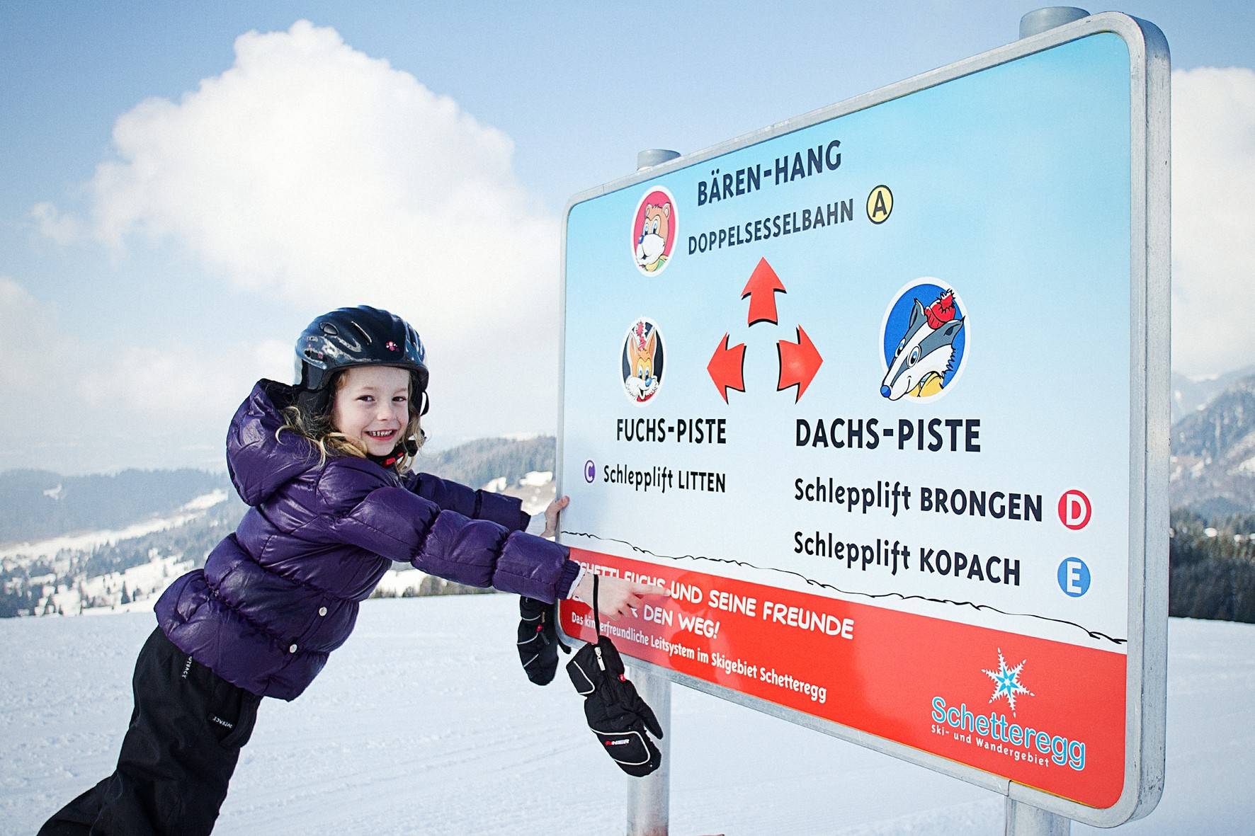 Mädchen am Wegweiser des Kinder-Pistenleitsystems mit Fuchs- und Dachs-Piste
